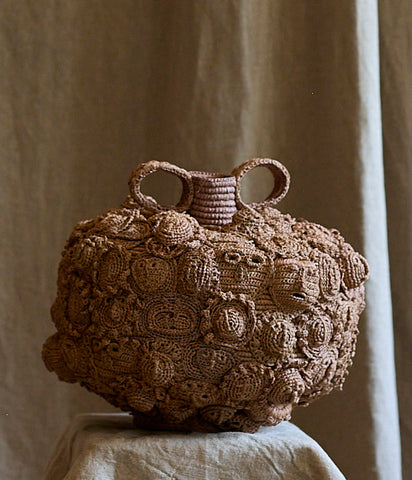 Amphora decorated with masks and faces in raffia by Natalia Brilli 